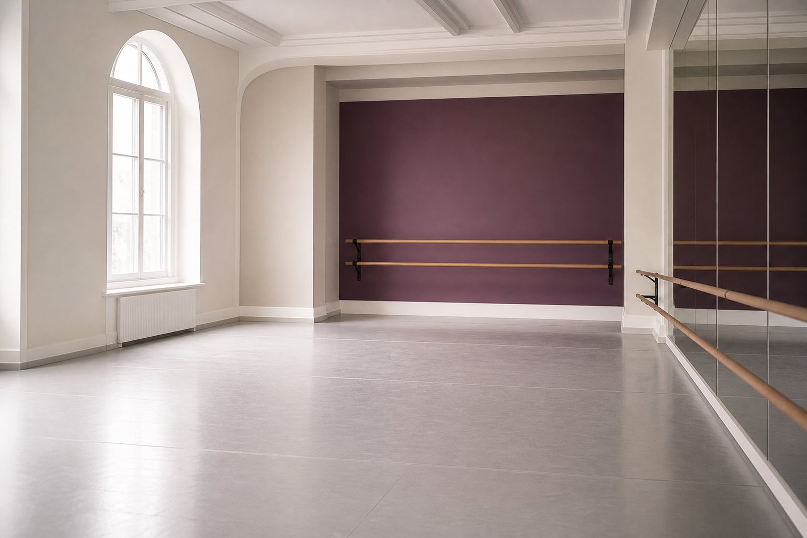 An empty ballet studio with a wooden barre, mirrors and a sprung floor lit by soft daylight
